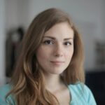 Close-up portrait of a young freckled woman indoors, expressing calm and beauty.